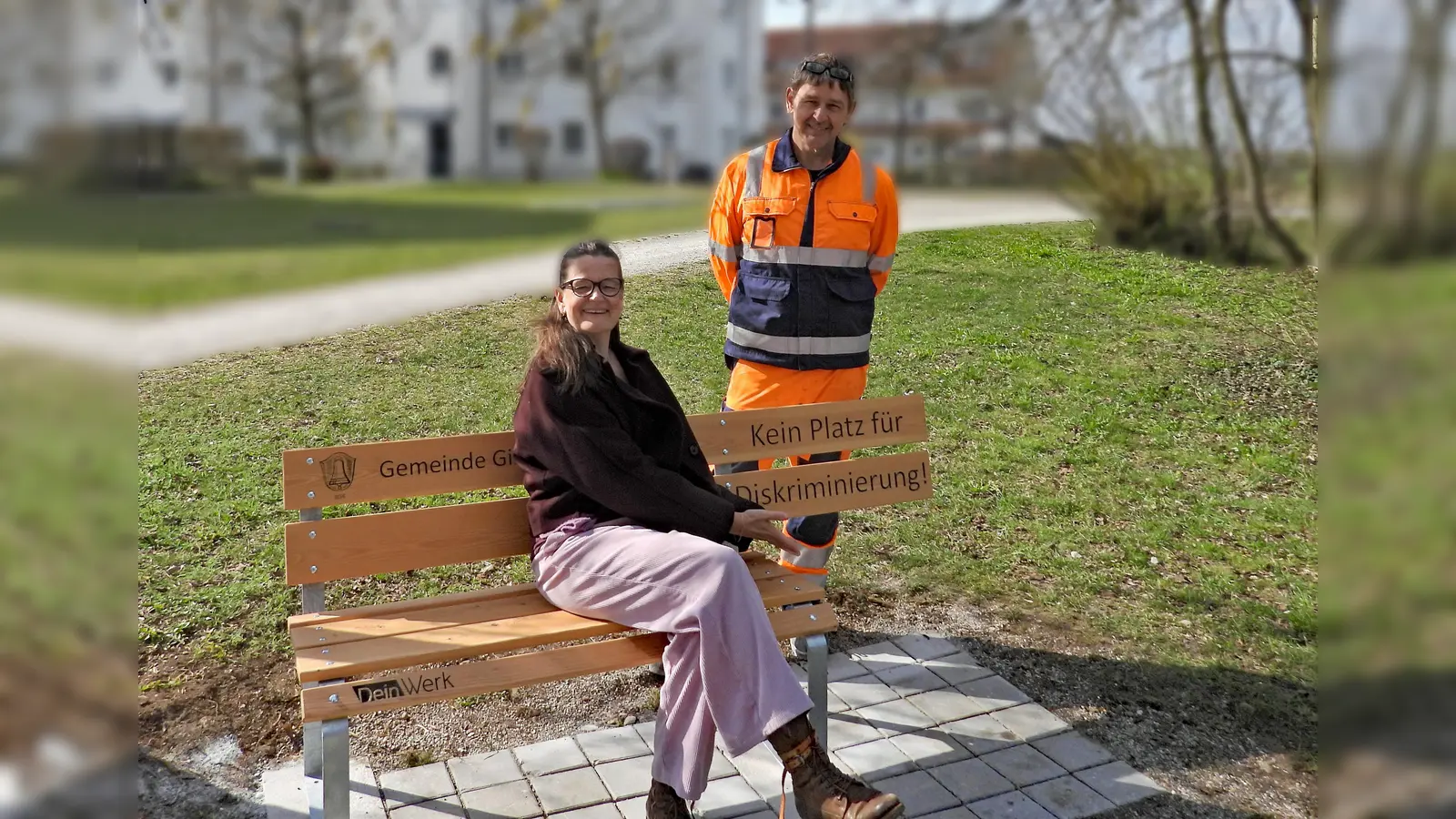 Sabine Ayhan (Inklusionsbeauftragte) und Bauhofmitarbeiter Jürgen Grübler bei einer der neuen Bänke gegen Diskriminierung. (Foto: Gemeinde Gilching)