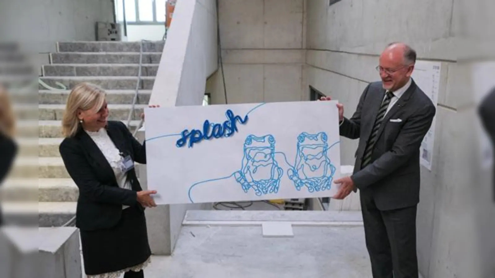 Drs. Rudolph Ensing (re.: Schuldirektor) und Dr. Alexia Giannakopoulou (li.: zukünftige Schuldirektorin der Grundschule) stellen das Design vor, das zukünftig die Treppenhäuser des Neubaus schmücken werden.  (Foto: Europäische Schule)