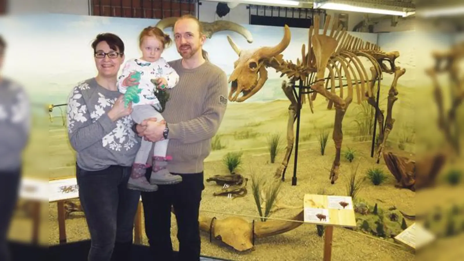 Die Jubiläums-Besucherin Milla mit ihren Eltern neben einem echten 30.000 Jahre alten Bisonskelett.	 (Foto: Uhrzeitmuseum)