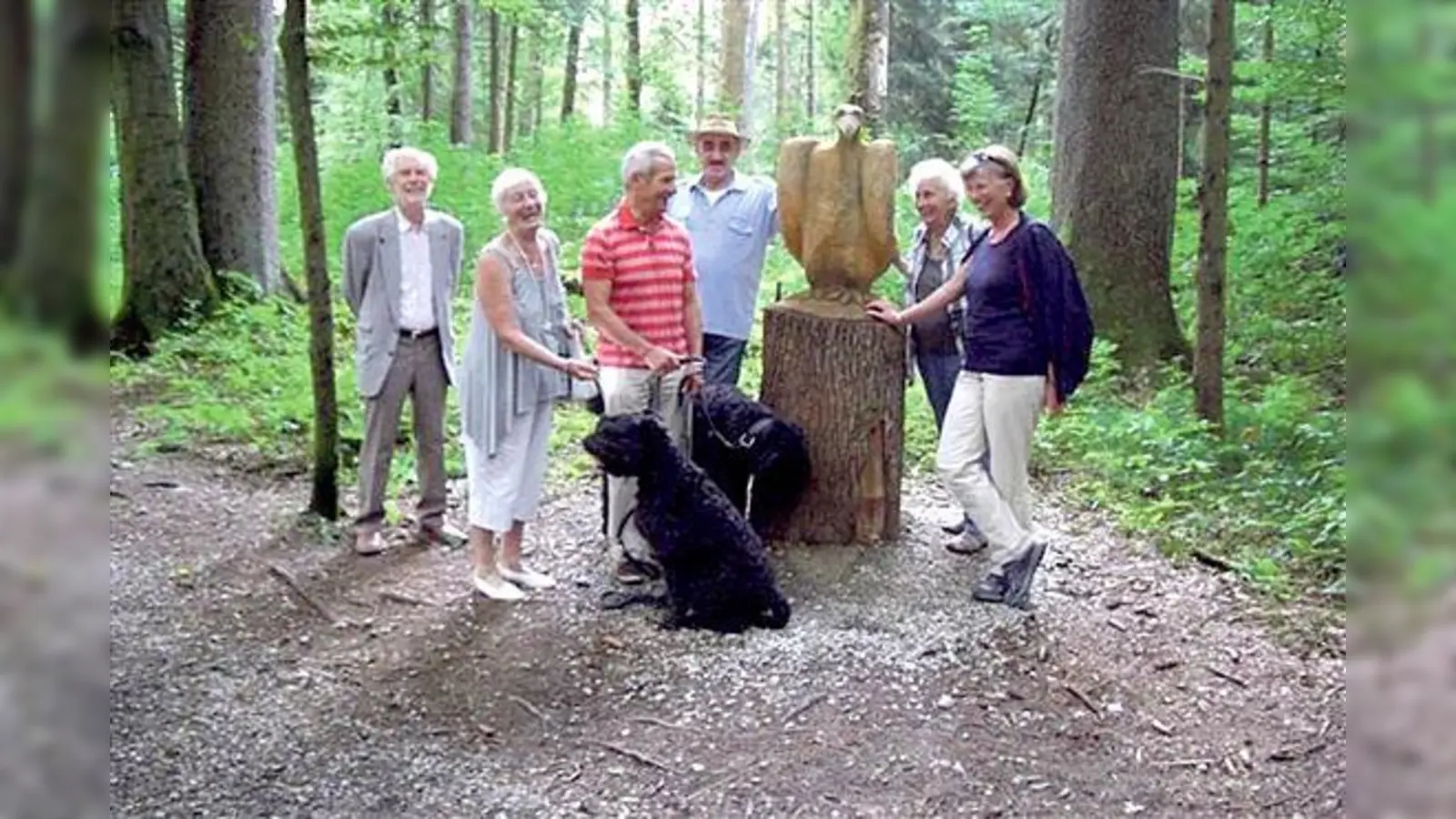 Die Teilnehmer mit ihren vierbeinigen Lieblingen herumgruppiert um den aus einem Baumstamm geschnitzten Adler auf dem neu hergerichteten Waldlehrpfad. 	 (Foto: VA)