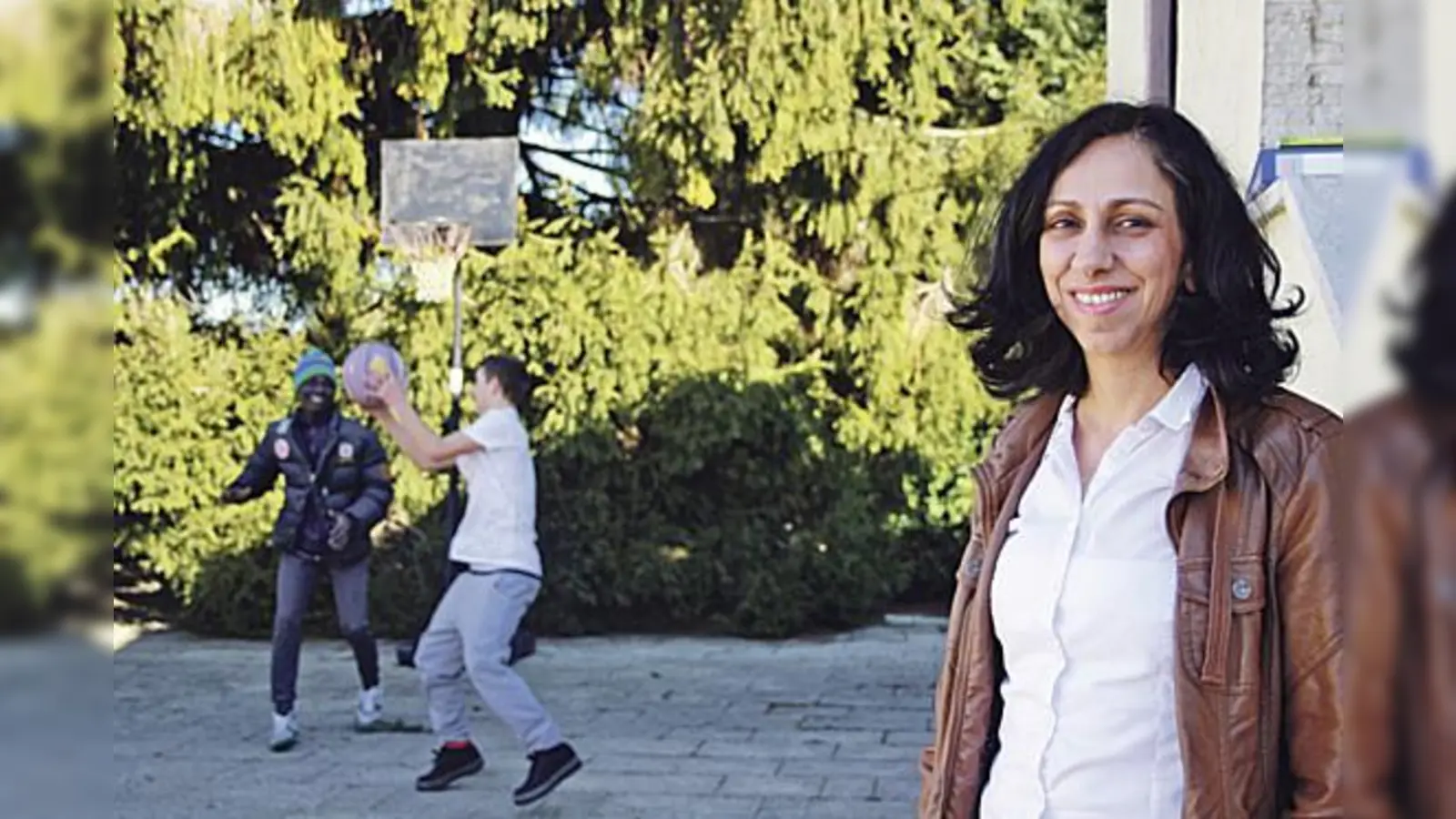Atisa Lunghammer, Leiterin der ZIO, und einige minderjährige Flüchtlinge, die vor dem Haus der Diakonie Hasenbergl Basketball spielen.	            (Foto: js)