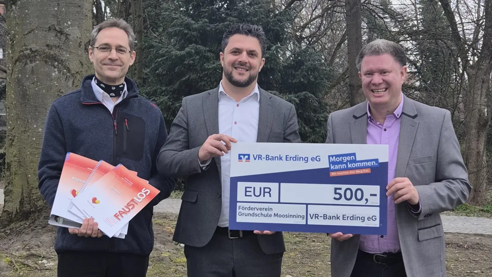 Thomas Gobmaier (Vorsitzender des Fördervereins GS Moosinning), Hamdi Salishta (VR Bank Erding eG) und Thomas Speyerer (stellv. Vorsitzender des Fördervereins GS Moosinning) präsentieren den Spendenscheck und einen Teil des beschafften „Faustlos“-Materials (von links). (Foto: red)