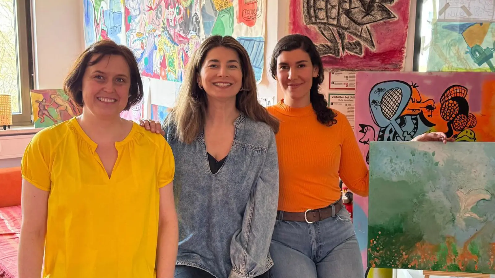 Die Zwischennutzung in der Eschenpassage geht weiter. Darüber freut sich die Initiatorin, Vhs-Vorsitzende Naciye Özsu (Mitte), mit Schnittdirektrice Roswitha Töchterle (links) und Acrylmalerin Ebru Albayrak-Kayabasi (rechts mit eigenem Acrylbild). Die Bilder im Hintergrund sind von Zwischennutzungsmieter Johannes Dettendorfer. (Foto: job)