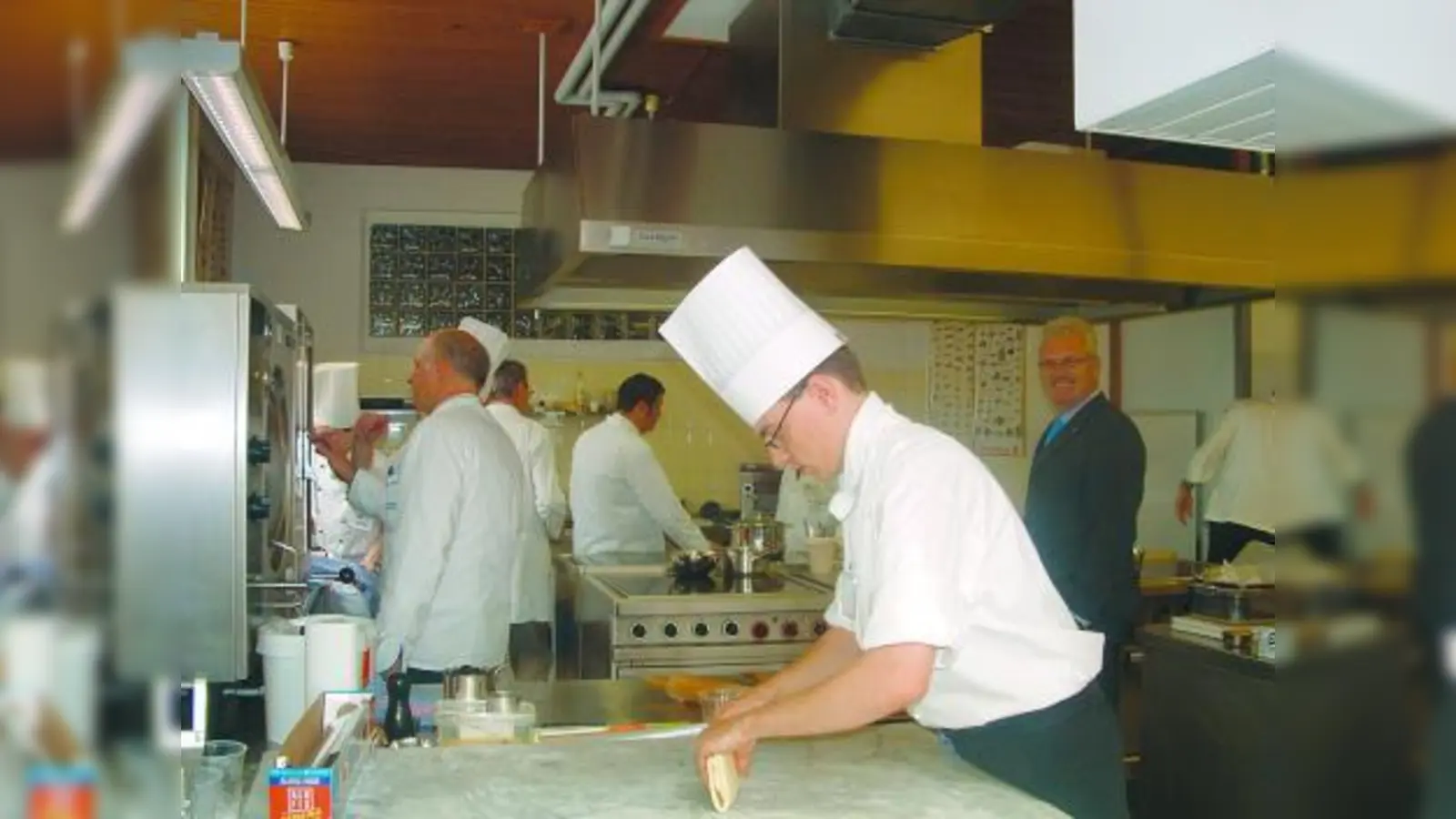Der Prüfungsstress ist nicht zu unterschätzen: Unter den wachsamen Augen der Prüfer bereiteten die Küchenmeister-Anwärter ein Fünf-Gänge-Menü zu. Rechts: Kermess-Leiter Hans Passian, der sich sehr freute, als schließlich bekanntgegeben wurde, dass alle Prüflinge bestanden haben. (Foto: bb)