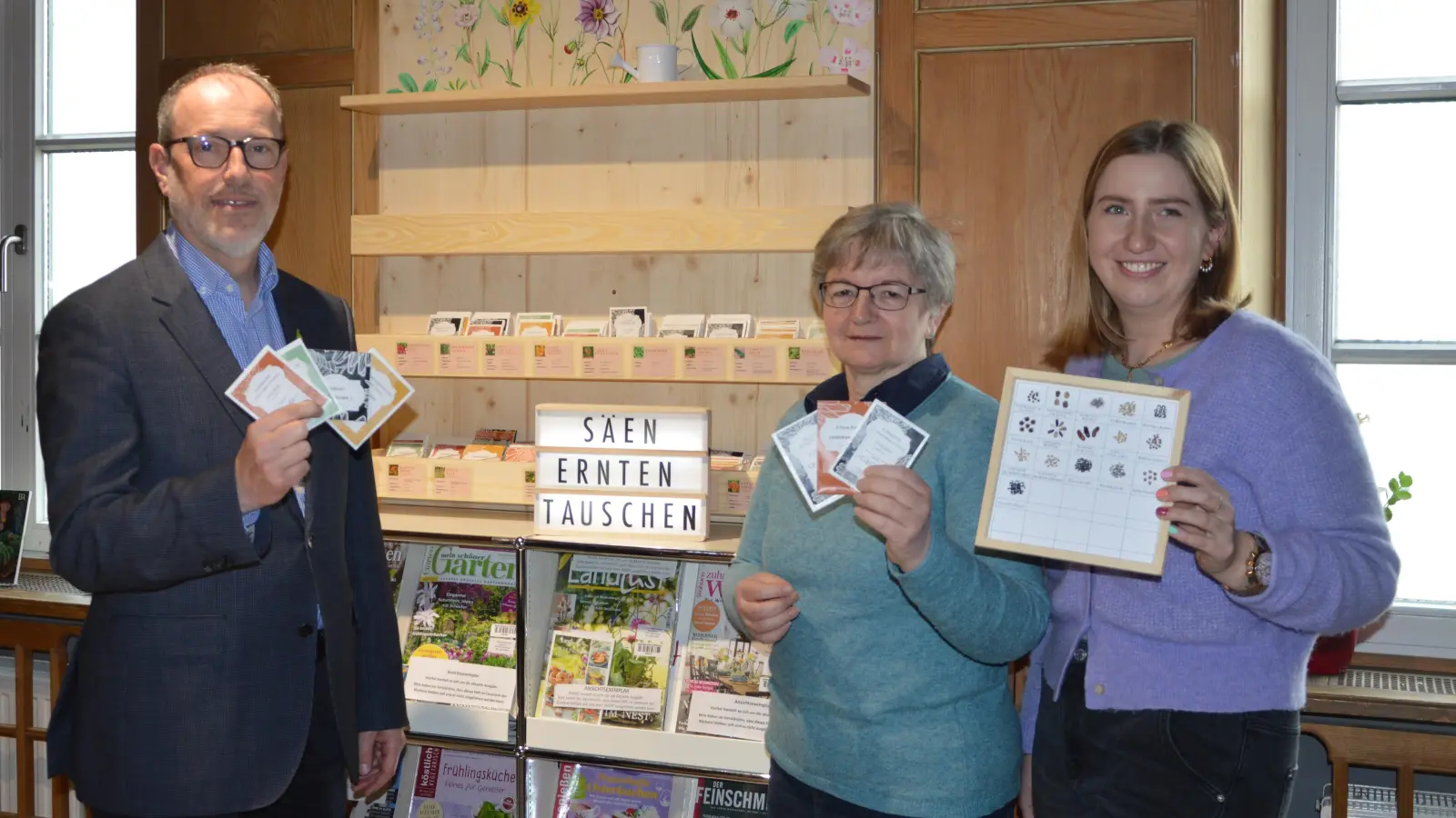 Bürgermeister Christoph Schmid, Ute Knopp (Leitung der Gemeindebücherei), Melanie Buchner (Standortförderung, Markt Holzkirchen) bei der Eröffnung der ersten Saatgutbibliothek (v.l.). (Foto: Gemeinde Holzkirchen)