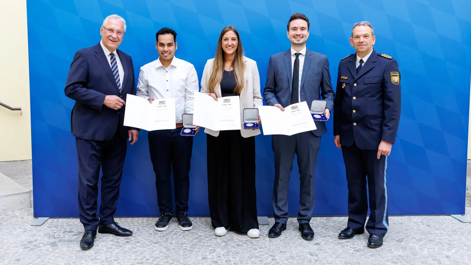 Innenminister Joachim Herrmann (links) und Landespolizeipräsident Michael Schwald (rechts) ehrten Mehdi Akhlaqi, Franziska Lechner und Burak Pilavcioglu (Zweiter bis Vierter von links). Diese griffen bei einem Angriff auf einem U-Bahnhof in München ein, als ein Mann seinem auf dem Boden liegenden, bewusstlosen Opfer mehrfach gegen den Kopf trat. (Foto: Matthias Balk/Bayerisches Staatsministerium des Innern, für Sport und Integration)