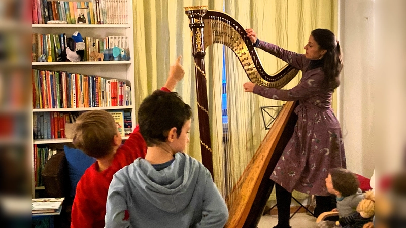 Harfenistin Sarah Cocco erklärt den bei der Vorleseaktion, wie die Harfentöne entstehen. (Foto: Kinderschutzbund Starnberg e.V.)