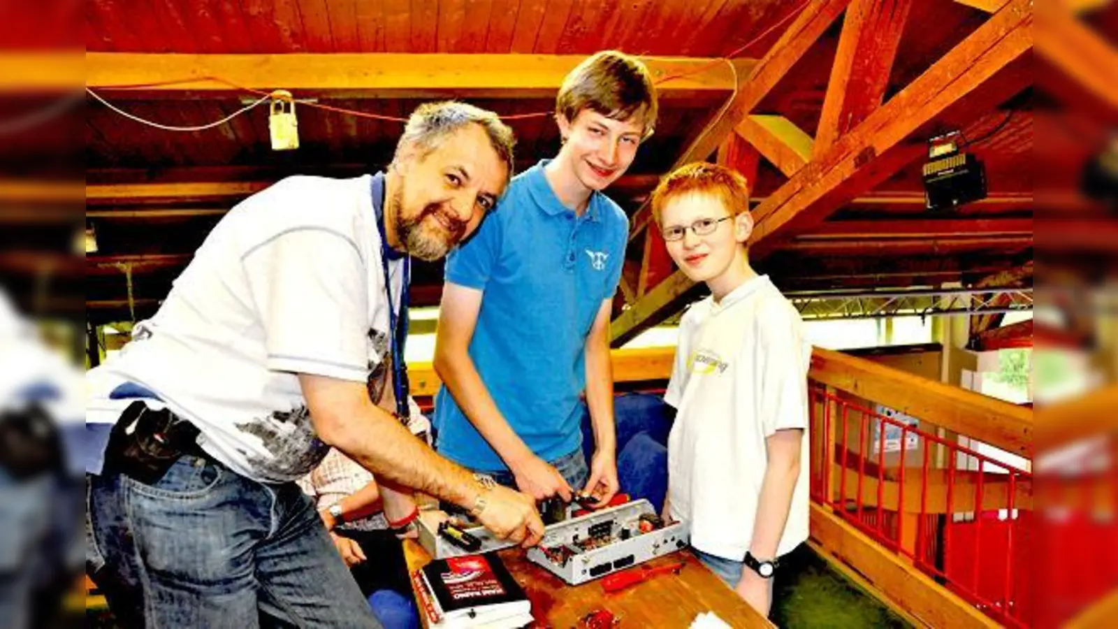 Werkstattleiter Markus Boehm erklärt Florian und Felix, welche Teile man in dem alten Receiver wiederverwenden kann. 	 (Foto: Sybille Föll)