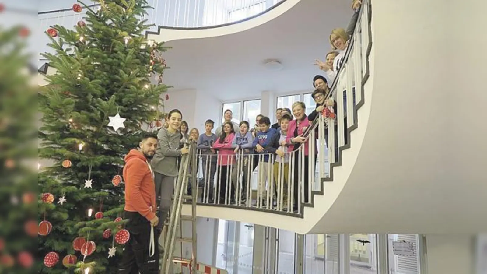 Regierungspräsidentin Brigitta Brunner mit den Schülerinnen und Schülern der Klasse 5 c der Ernst-Barlach-Schule und dem geschmückten Christbaum im Foyer der Regierung von Oberbayern. 		 (Foto: Regierung von Oberbayern)