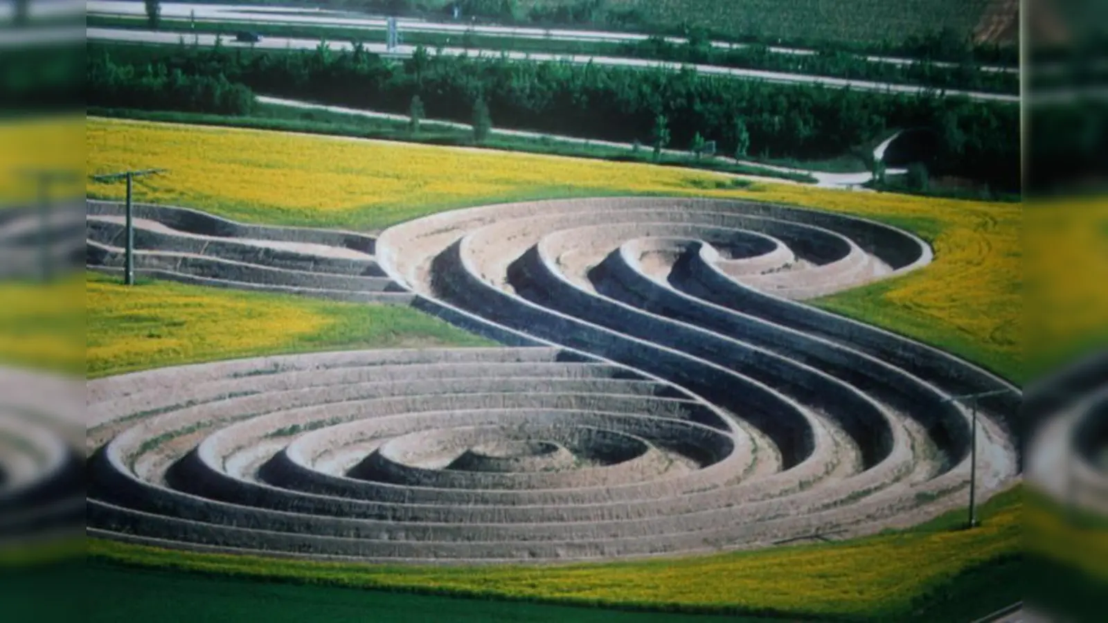 In den Feldern am Münchner Flughafen im Erdinger Moos, unmittelbar neben der Autobahnausfahrt und der Zufahrtsstraße zum Airport, ließ Wilhelm Holderied ein 270 mal 170 Meter großes Erdzeichen in Form einer Acht als eine „Insel für die Zeit”, als Auszeit und Innehalten im Alltagsstress, in den Boden einprägen. (Foto: WS)