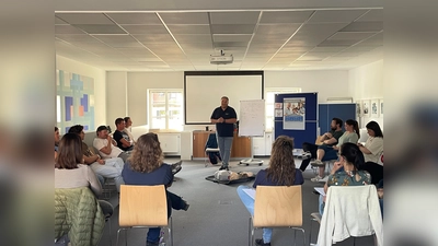 Ausbilder Michael Karlstetter demonstriert den jungen Eltern, wie man schnell und sicher Erste Hilfe leistet. (Foto: VR Bank Dachau)