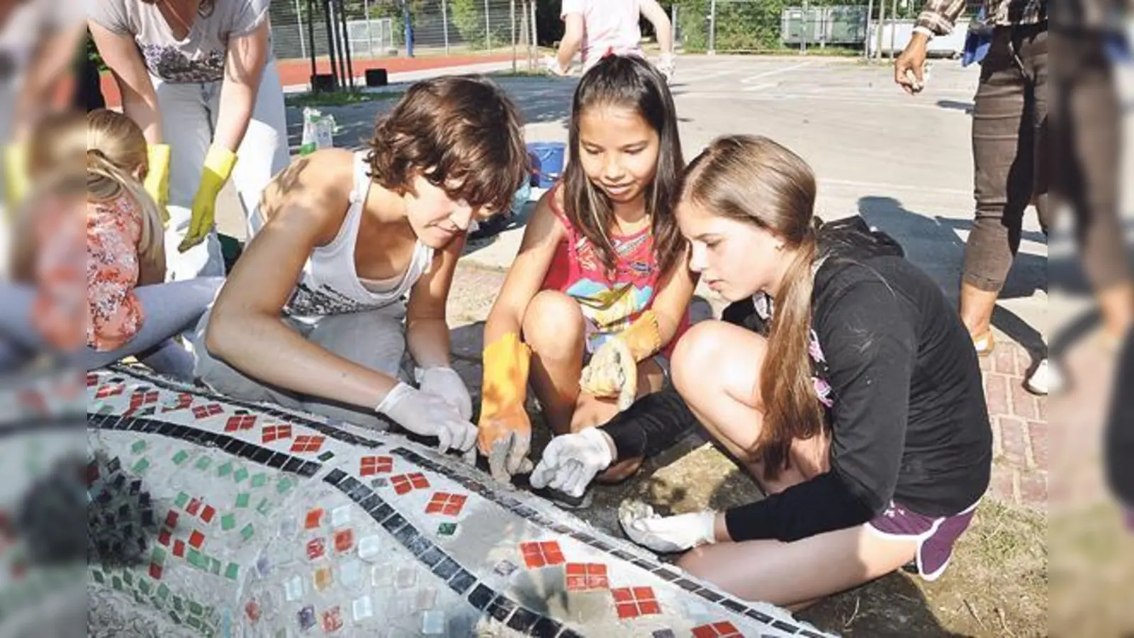 Silvia Gonzalez von Green City e.V. zeigt den Kindern, wie die Mosaiksteine gesetzt werden.  (Foto: Föll)