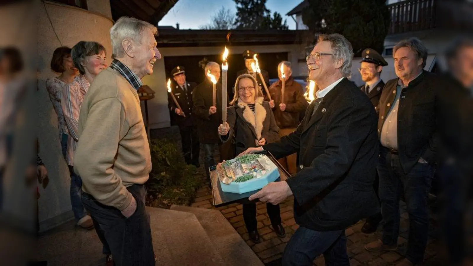 Alfred Pfeiffer mit seiner Frau und Tochter im Hintergrund, Bürgermeister Heinrich Hofmann überreicht das Geschenk umringt von Anneliese Bradel, Martin Fladerer und Martin Götz. (Foto: Gemeinde Planegg)