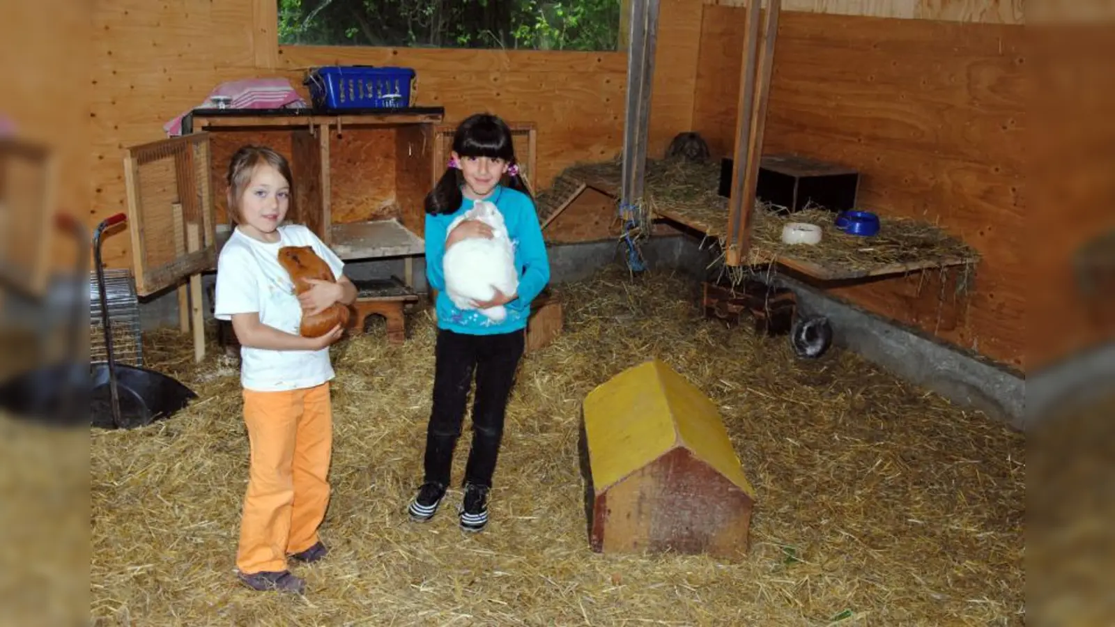 Marie (links) und Jine gehören zu den „Farmkindern“, denn sie haben sich verpflichtet, einmal in der Woche die Pflege eines bestimmten Tieres zu übernehmen – und das gemeinsame Ausmisten des Kleintierstalles gehört auch dazu. (Foto: Eva Schraft)