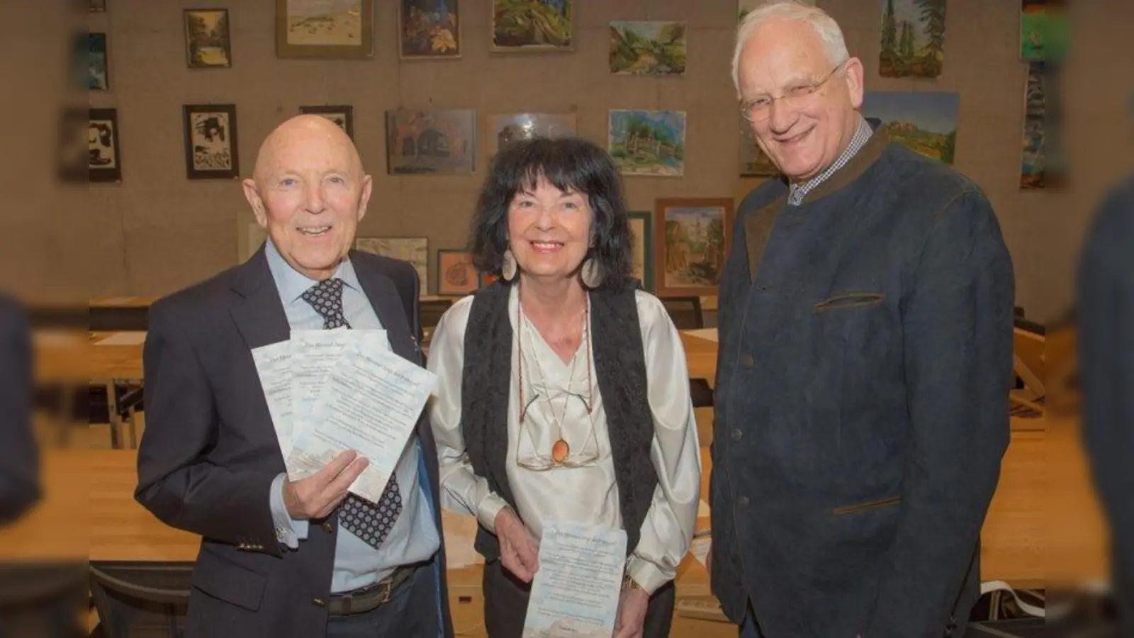 Dr. Martin Dorn mit seiner Frau Christina und dem zweiten Bürgermeister Hans-Jürgen Böckelmann vor der Ausstellungswand im Sitzungsaal des Rathauses (von links). (Foto: Gemeinde Herrsching)