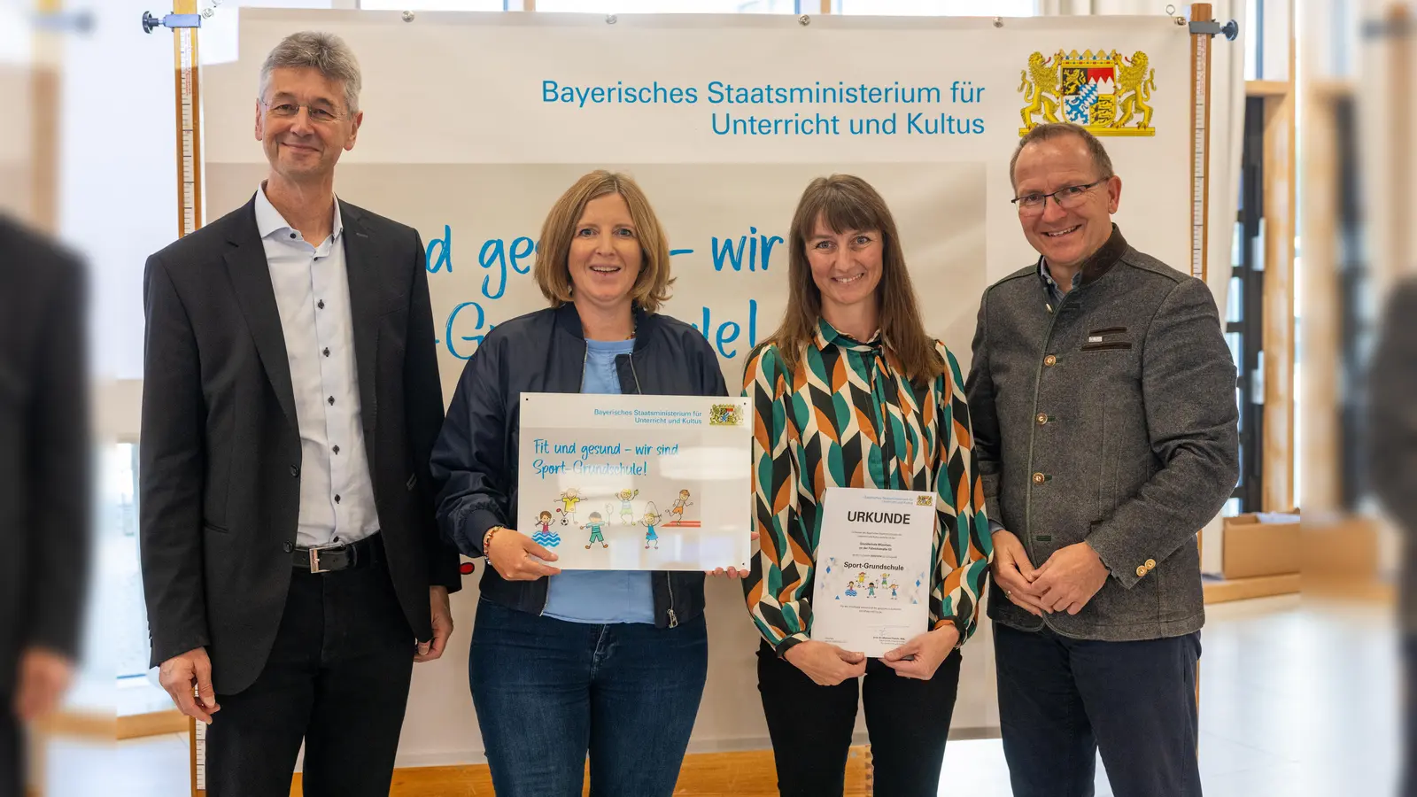 Kultusminister Michael Piazolo (links) und der Präsident des Bayerischen Landessportverbands, Jörg Ammon (rechts), überreichten die Urkunde an die Grundschule an der Führichstraße. (Foto: Alexandra Beier)