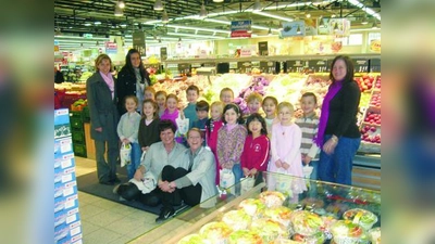 Gerhardine Maurus und Tanja Mayer (vorne) vom HIT-Markt Laim überreichten den Kindern vom Kindergarten Heilige 12 Apostel - hier mit ihren Betreuerinnen - prall gefüllte „Fruchttüten” mit frischem Obst. (Foto: pi)