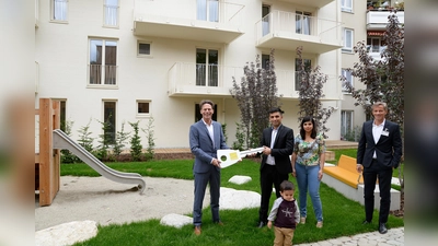 Klaus-Michael Dengler (links), Familie Nori und Axel Fischer bei der Schlüsselübergabe. (Foto: Gewofag)