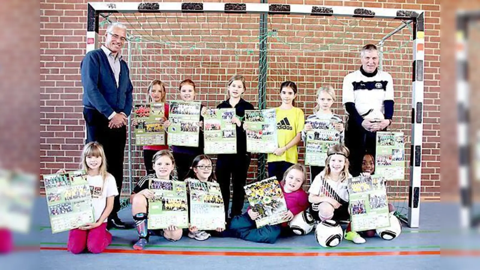 JFG-Chef Hans Egger (l.) und Übungsleiter Norbert Göbeler (r.) brachten den Mädchen vom Lodererplatz den Erdinger Fußballkalender mit, in dem auch die beiden Sport-nach-1-Mannschaften zu sehen sind. 	 (Foto: Priglmeir)