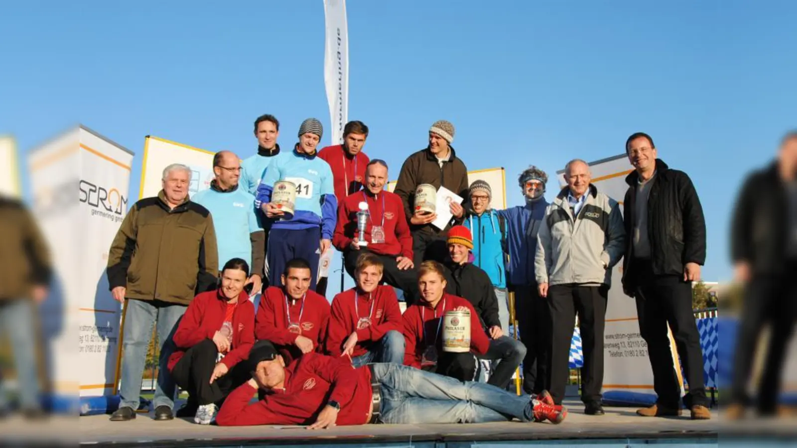 Beste Stimmung bei der Siegerehrung zur Firmenwertung im Hauptlauf: Oberbürgermeister Andreas Haas und Peter Schichl (von rechts) gratulierten den vielen Läufern der Schmankerlmetzgerei Germering zum Sieg und den Mannschaften Gasversorgung Germering zum zweiten (hellblaue Trikots) sowie Thermo Fisher Scientific zum dritten Platz – Gewerbereferent Albert Metz (links) über die Partyfässchen. (Foto: Eva Schraft)