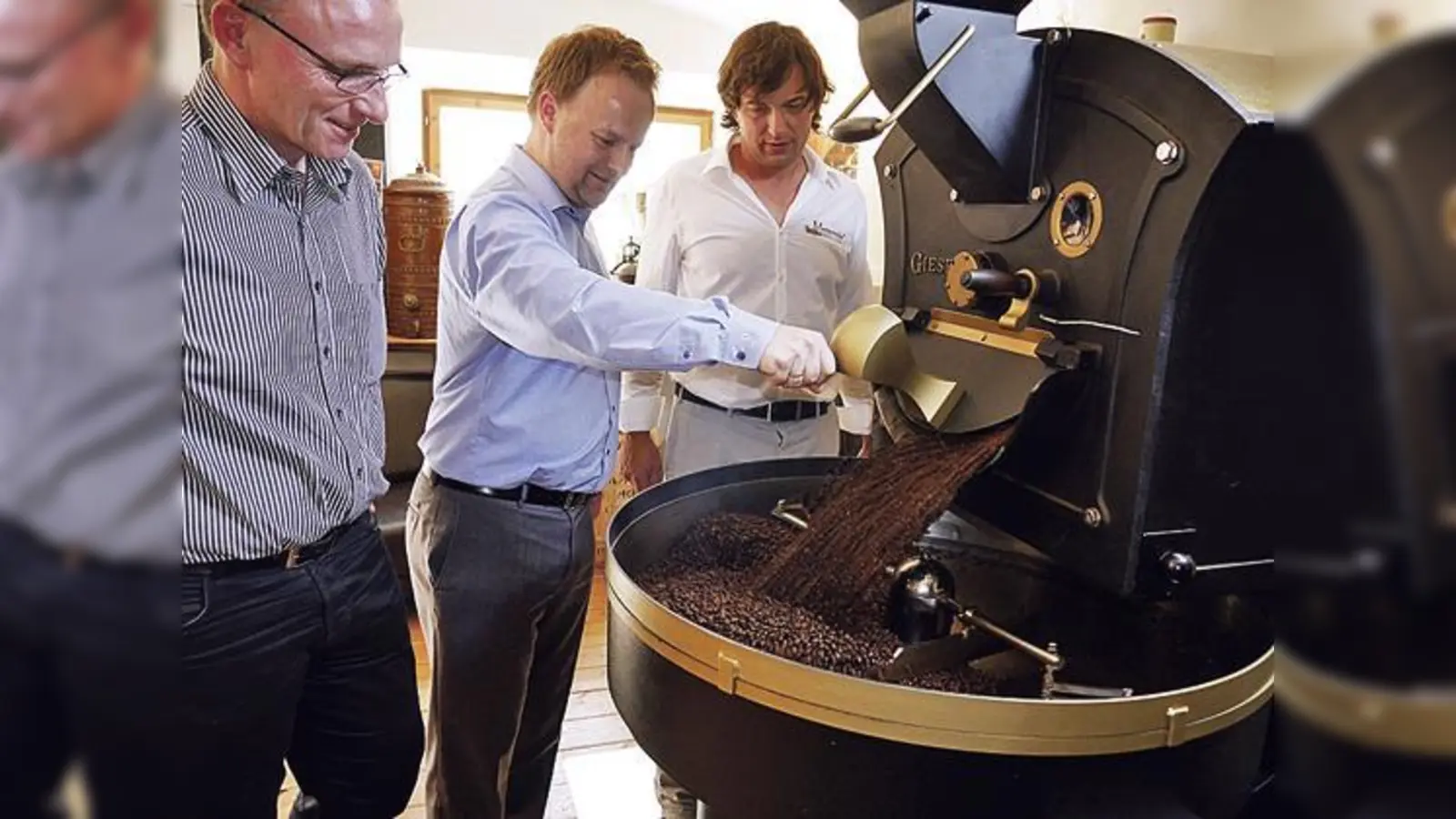Bürgermeister Hans Fent (v.l.), Robert Niedergesäß und Ralf Heincke vor der Kaffeeröstmaschine. 	 (F: LRA)