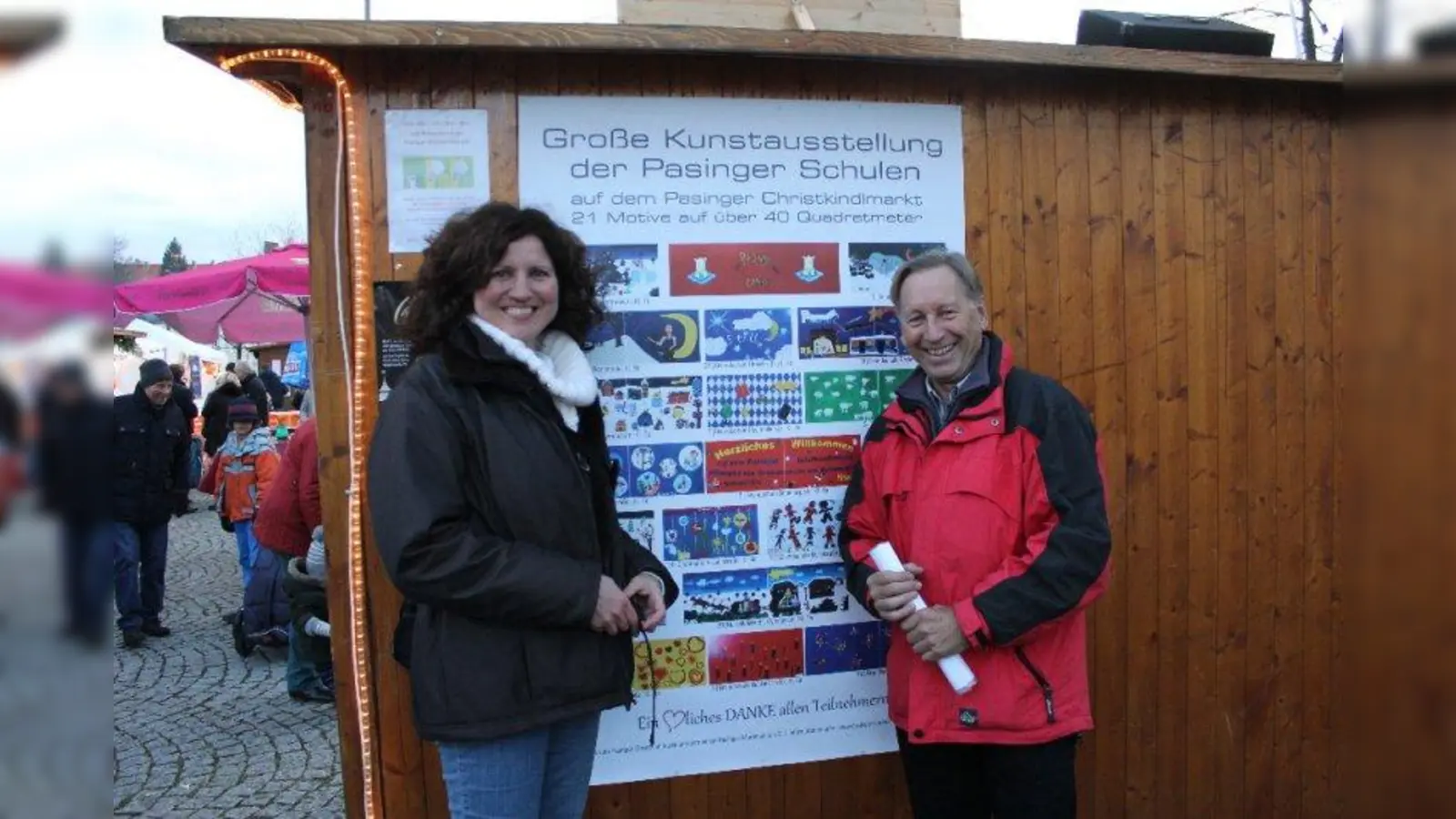 Pasinger Erst- bis Neuntklässler gestalteten die Standklappen. Die Initiatoren und Organisatoren Antje Hertel und Helmut Lippah vor dem Plakat aller Schüler-Kunstwerke. (Foto: US)