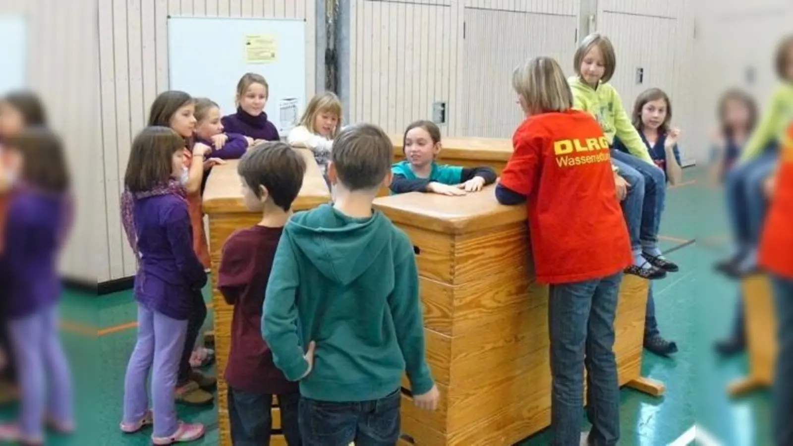 Eine DLRG-Ausbilderin lehrt richtige Verhaltensregeln auf zugefrorenen Gewässern: Turnkästen sollen dabei ein Eisloch simulieren. 	 (Foto: DLRG)