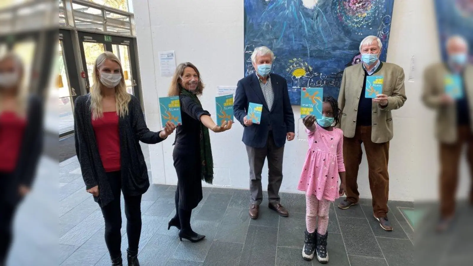 Übergabe mit Abstand (von links): Lesebeauftragte und Lehrerin Sonja Schinzel, Rektorin Margit Baran-Lander, Dr. Axel Därr, Dr. Hannes Schaber (beide Mitglieder des Rotary-Clubs) und im Vordergrund Schülerin Oluwadara (Klasse 2b). (Foto: Grundschule Martinsried)