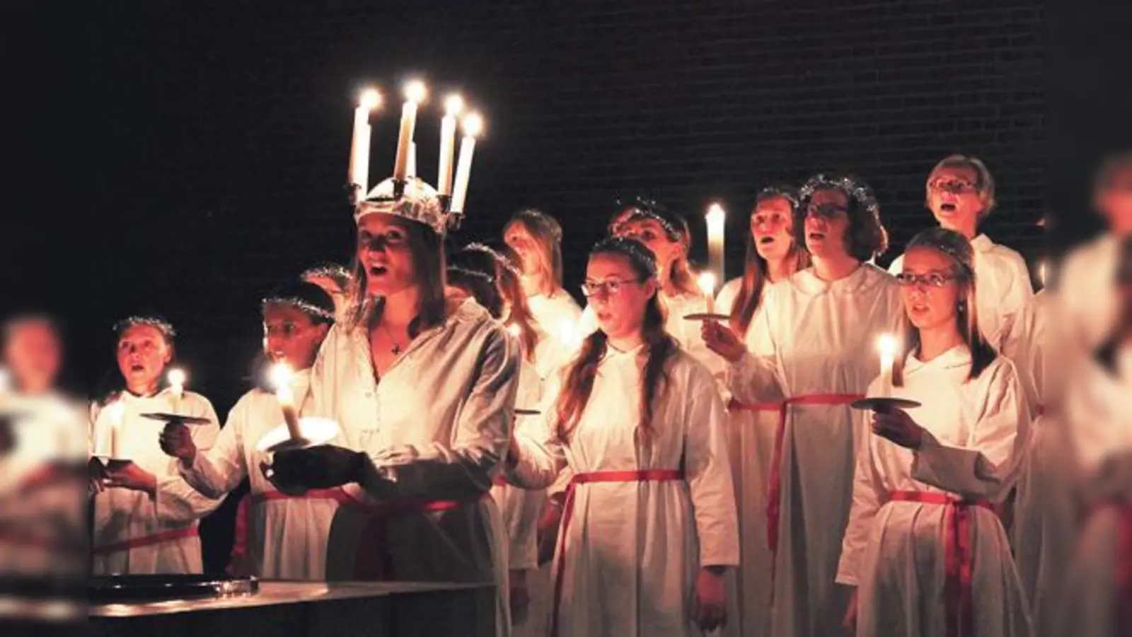 Die Lichterkönigin Lucia erscheint mit Kerzen auf dem Kopf und Gefolge.	 (Foto: Schwedischer Chor München)