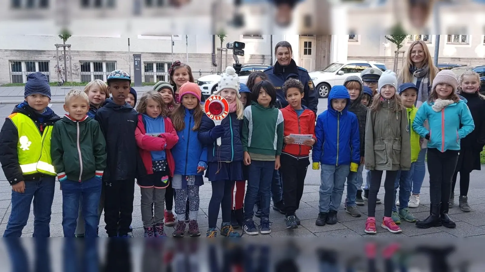 Stoppten Verkehrssünder vor der Grundschule an der Implerstraße: die Kinder der 2a mit ihrer Lehrerin Marie Gandl und Polizeihauptmeisterin Marion Münster. (Foto: PI 15/Sendling)