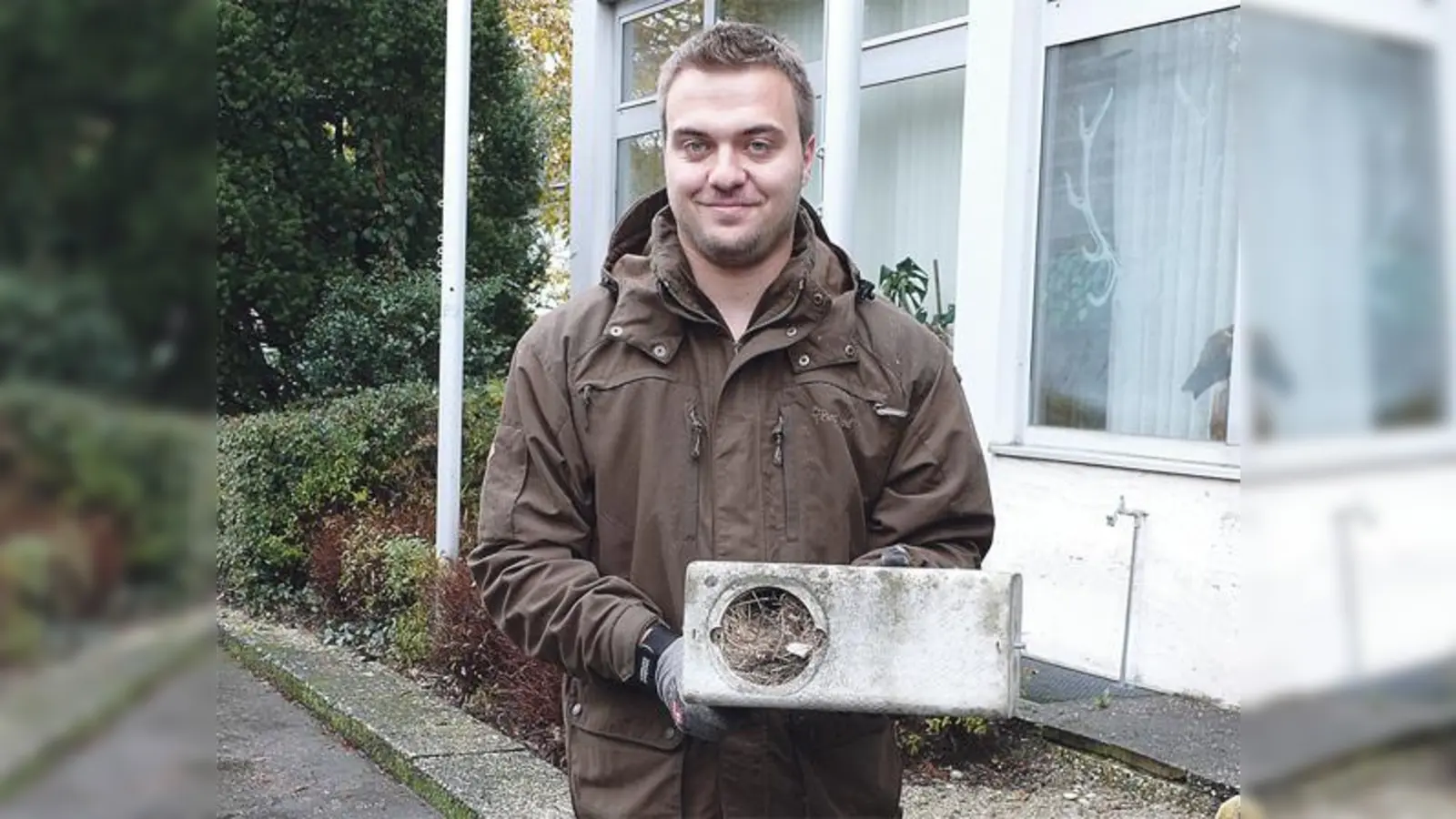 Praktikant Sebastian Riedl mit einem bis zum Rand gefüllten Nistkasten, der sonst an der Dachrinne angebracht ist. Am Haus der Bayerischen Jäger in Feldkirchen brüten vor allem Mauersegler. 	 (Foto: Wildland-Stiftung Bayern)