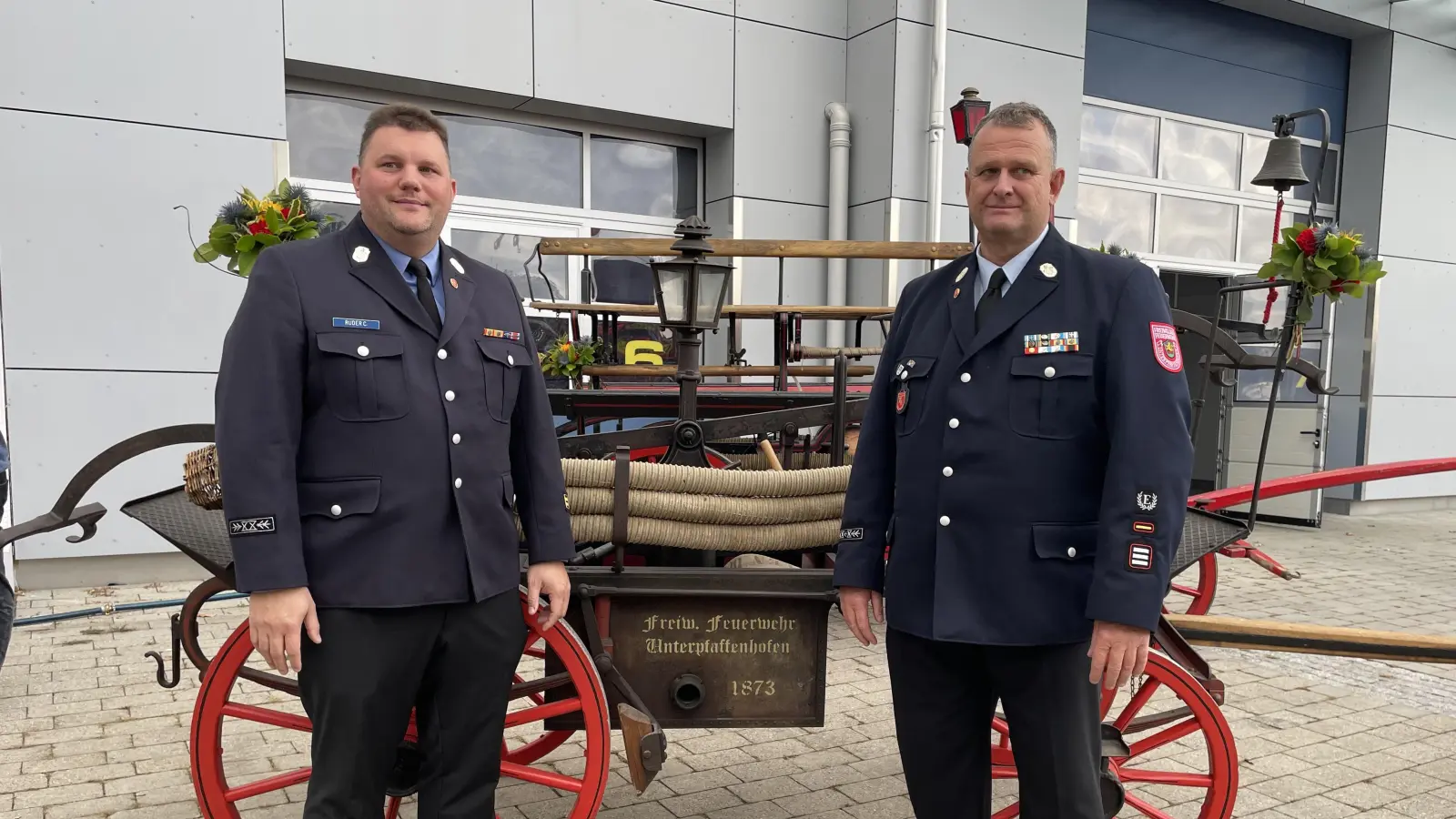 Der aktuelle Kommandant Christian Ruder (l.) und sein Vorgänger Michael Gogl vor dem historischen Spritzenwagen. (Foto: pst)