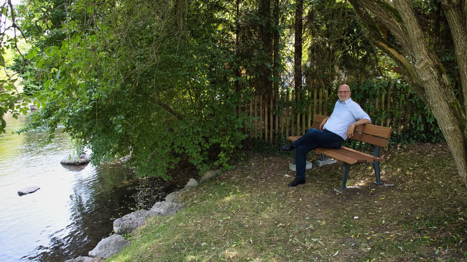 Rudolph Haux sitzt auf der neu aufgestellten Bank am Badeplatz beim alten Rathaus. (Foto: Gemeinde Krailling)