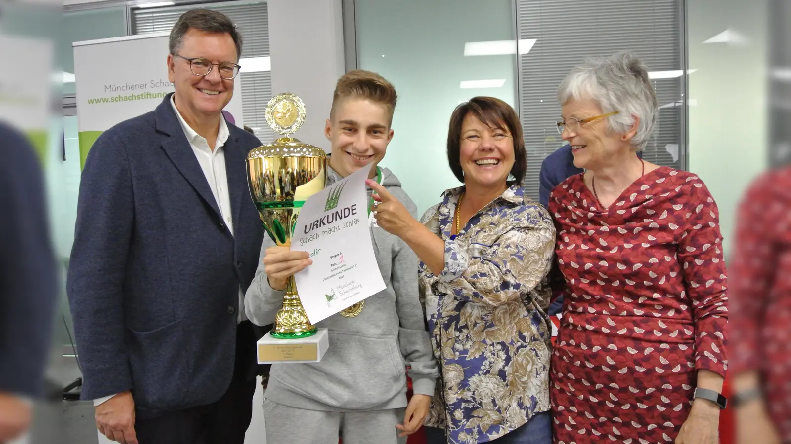 Stiftungsgründer Roman Krulich (li.) freut sich mit Kadir, dem Gesamtsieger, Ehrengast Diana Stachowitz (2. v. re.) und Schirmherrin Angelika Speck-Hamdan (re.). (Foto: Münchener Schachstiftung)