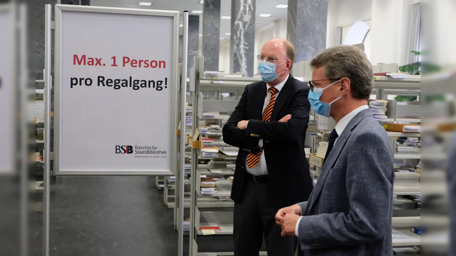 Kunst- und Wissenschaftsminister Bernd Sibler (r.) überzeugt sich zusammen mit dem Generaldirektor der Bayerischen Staatsbibliothek Dr. Klaus Ceynowa (l.) von den Hygiene- und Sicherheitsmaßnahmen bei der Ausleihe. (Foto: BSB)