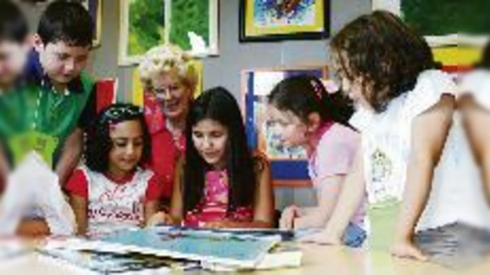 Während Sumeyye (Mitte) vorliest, folgen die anderen Kinder dem Text und lernen so ganz nebenbei lesen. Karin Reimann hilft weiter, wenn es Schwierigkeiten gibt.  (Foto: cr)