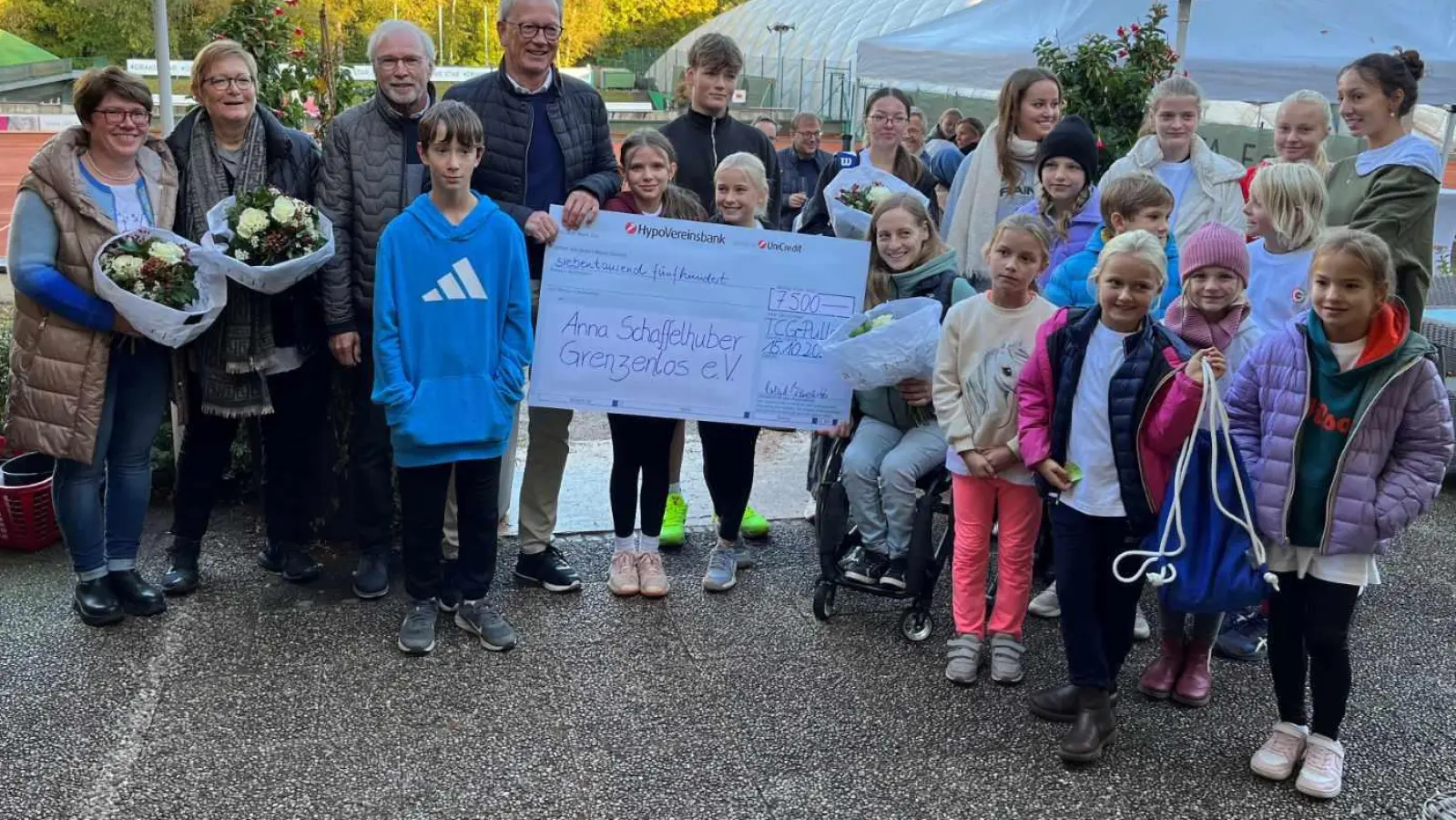 TCG-Sponsor und Charity-Cup-Schirmherr Ralph Büschl (4.v.li.) übergibt den Scheck über 7.500 Euro zusammen mit dem TCG-Vorstand um TCG-Präsident Roland Benedikt (3.v.li.) und TCG-Vorstand Mitglieder Dr. Verena Fritzemeyer (2.v.li.) sowie Teilnehmern des 5. Charity Cup an Anna Schaffelhuber (sitzend; rechts neben dem Scheck) vom Grenzenlos e.V. (Foto: TC Großhesselohe)