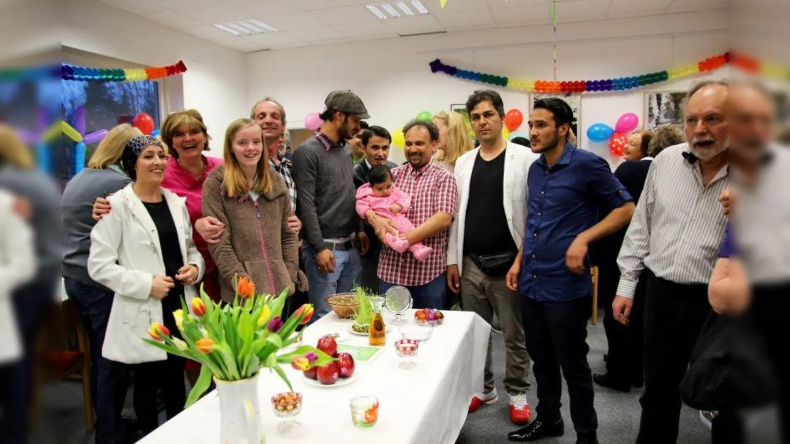 Welches Jahr schreiben wir 2017 oder 1396? Egal!  Kraillinger Ehrenamtliche des Helferkreises und Flüchtlinge feierten gemeinsam im Bürgerhaus Hubertus das persische Neujahrsfest Nouruz. Am traditionellen Zeremonientisch „Haft SIn” Britta Metius (2.v.l.) vom Helferkreis mit vielen Gästen und Freunden. (Foto: us)