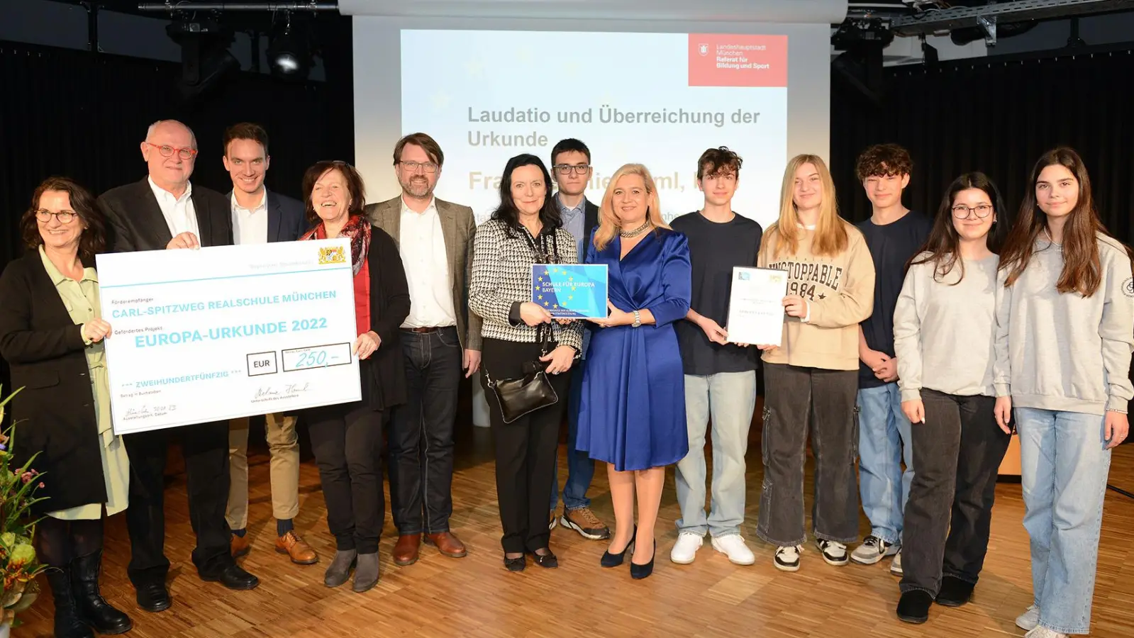 Staatsministerin Melanie Huml (Mitte) mit Schulleiterin Karin Müller-Franzen (neben Huml) und Münchens Stadtschulreferent Florian Kraus (5. v. li.), sowie Schüleren und Lehrern, die am Austausch teilgenommen haben. (Foto: Bayerische Staatskanzlei)