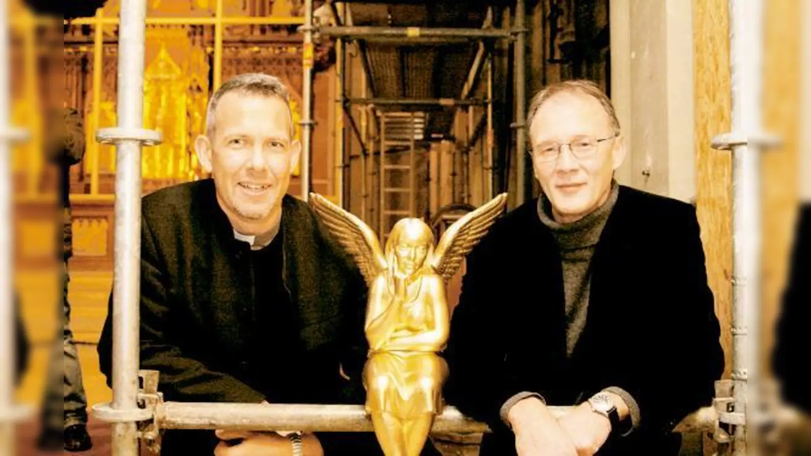 Der Künstler und sein Werk: Zusammen mit Engelbert Dirnberger (l.), Pfarrer der Kirche Heilig Kreuz, begibt sich der Skulpteur Ottmar Hörl ganz unter die Fittiche eines seiner 300 goldenen Schutzengel.  (Foto: mst)