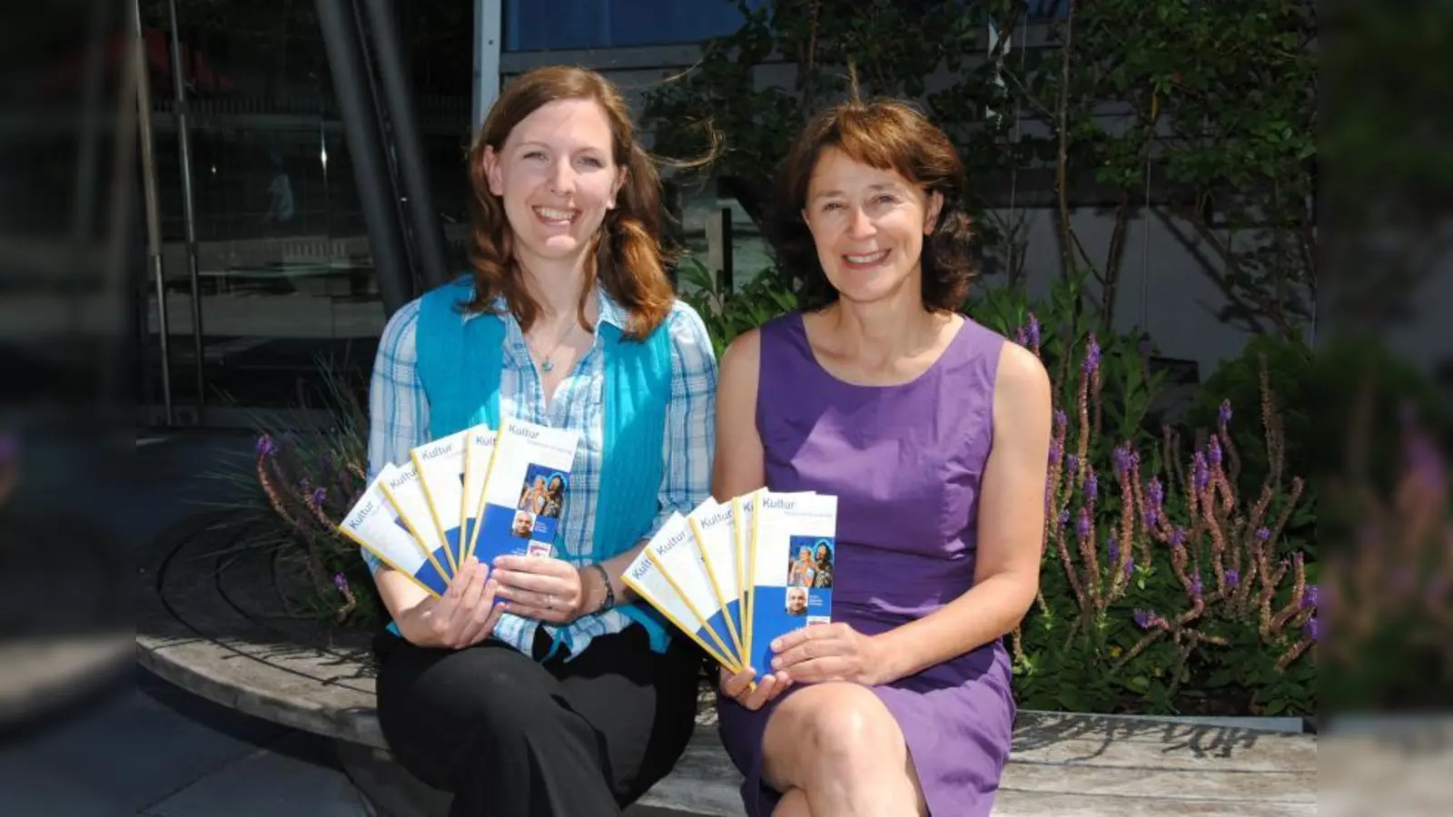 Stadthallenleiterin Medea Schmitt (rechts) und ihre neue Mitarbeiterin Stefanie Berger präsentieren hier das druckfrische Programmheft der Stadthalle Germering. (Foto: Eva Schraft)