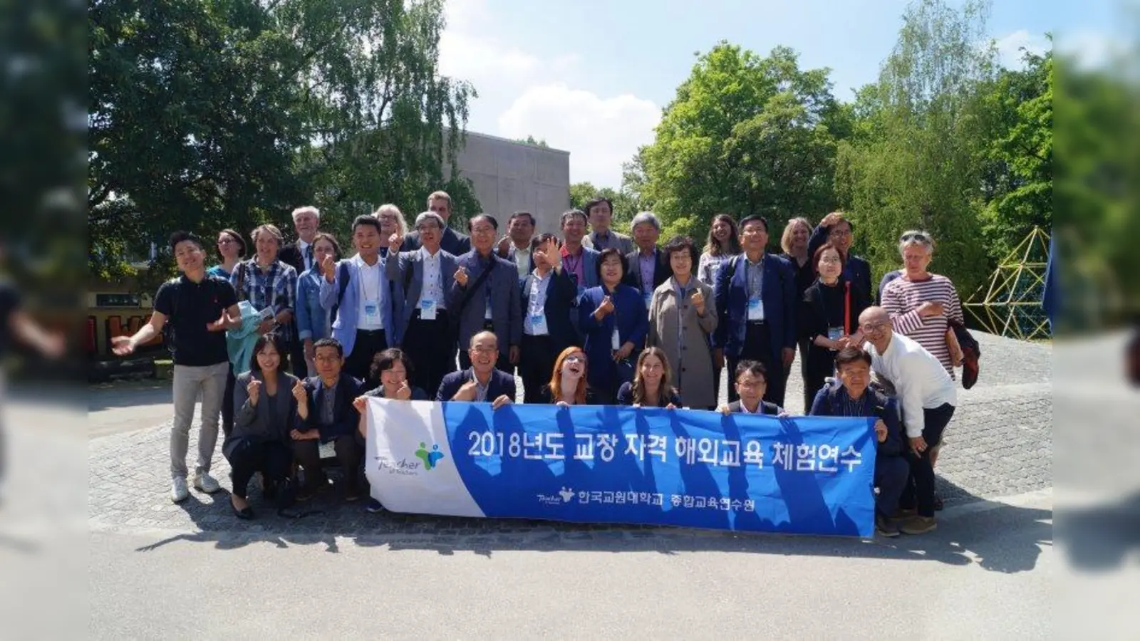 Die südkoreanischen Schulleiter stellen sich für ein Gruppenfoto auf dem Schulhof auf. Mit ihren Fingern formen sie ein „Herz”. (Foto: pst)