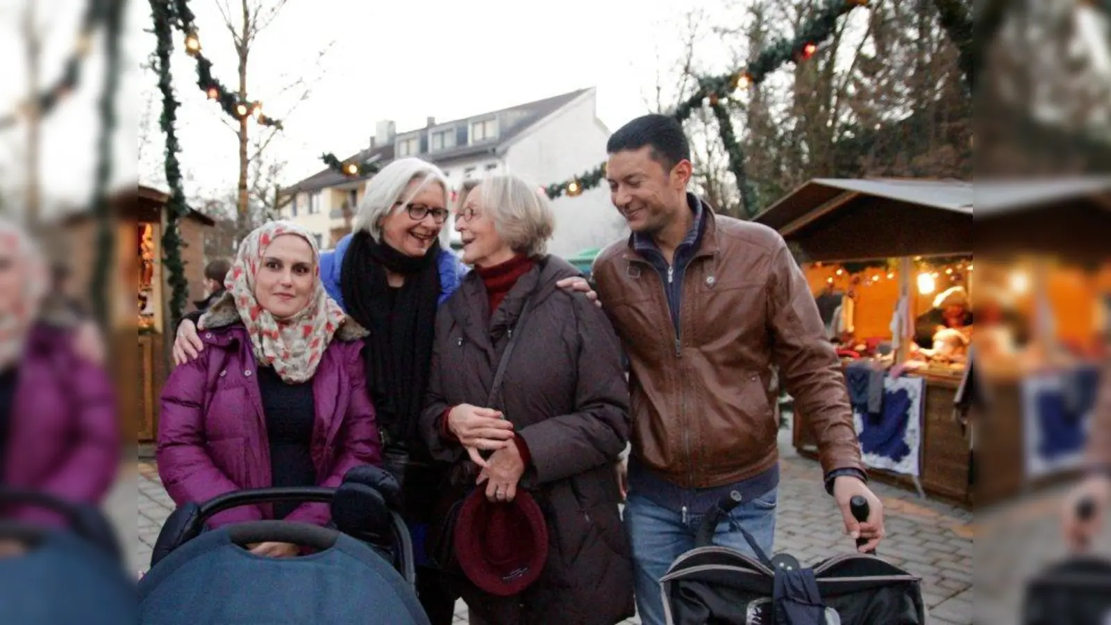 „Zeit schenken! Das ist das Wichtigste, dann wächst das Vertrauen.” Renate Hausdorf und Elisabeth Schneider-Eicke (Mitte, v.l.) vom Helferkreis mit Mariam und Ibrahim und ihren zwei kleinen Kindern auf dem Gräfelfinger Christkindlmarkt. (Foto: us)