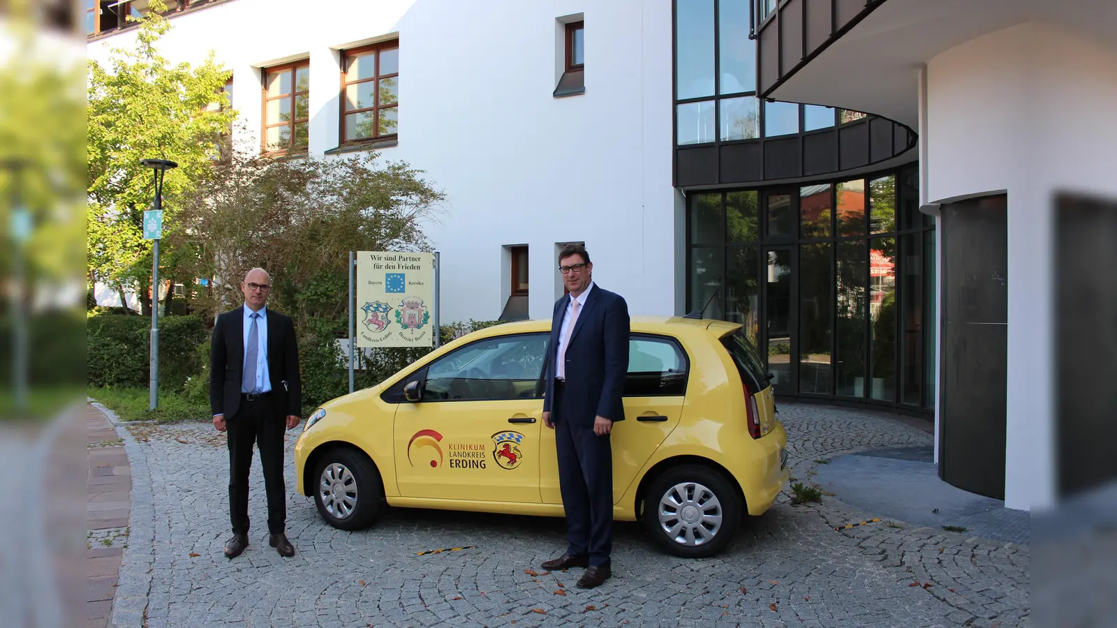 Landrat Martin Bayerstorfer und Krankenhausdirektor Dr. Dirk Last vor dem neuen sonnengelben Elektro-Dienstwagen des Klinikums Erding.  (Foto: LRA Erding )