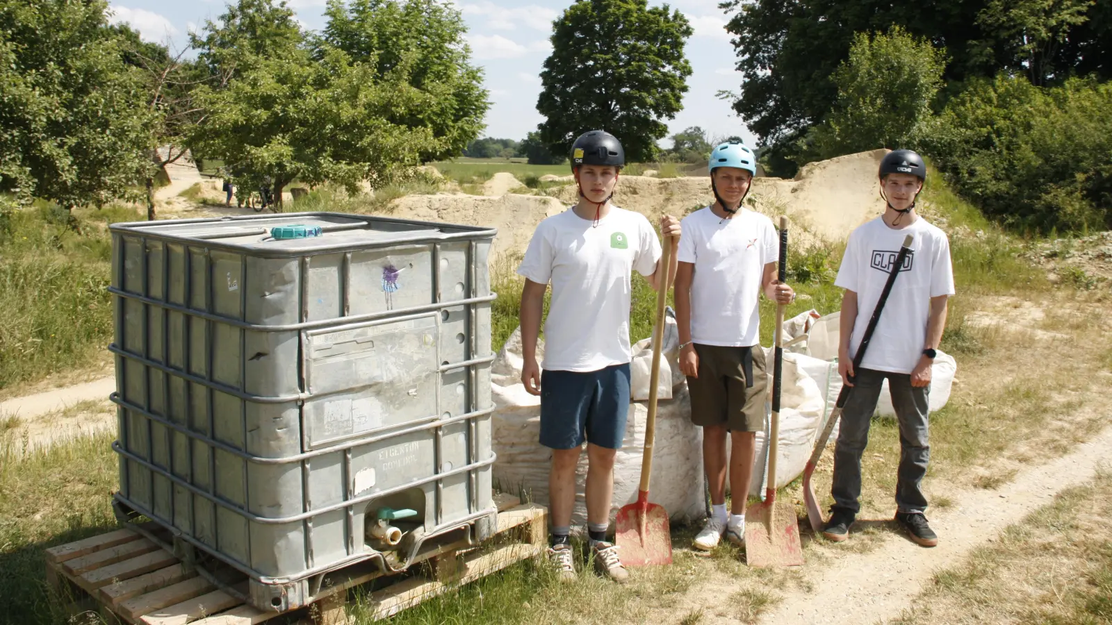 Alfred, Maxi und Georg (von links) vor dem Wassertank, den das Baureferat aufgestellt hat. Mit Lehm und Wasser lassen sich Reparaturen an der Anlage rasch ausführen. (Foto: job)