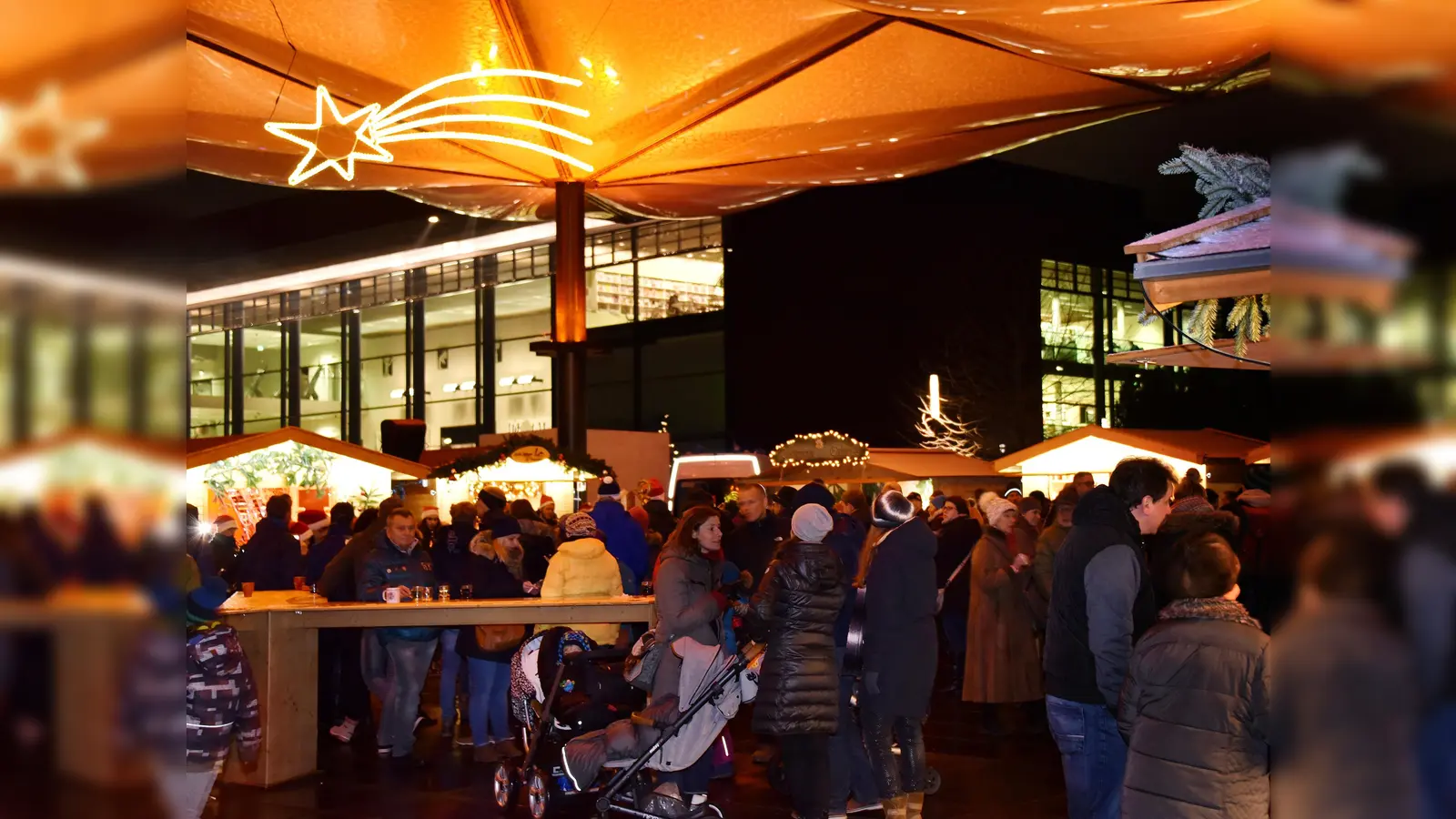 Unter dem Marktdach vor dem Unterföhringer Bürgerhaus genießen die Besucher des Christkindlmarktes die bunten Angebote der Markthütten. (Foto: Gemeinde UFG/foe)