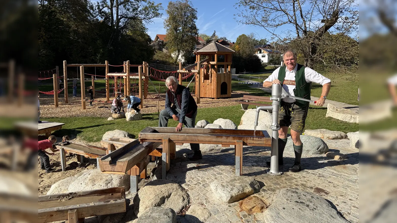 Bürgermeister Stefan Schelle (r.) testet mit Spielplatzplaner Peter Hohenauer vor der Eröffnung den Wasserspielbereich mit Pumpe.  (Foto: Gemeinde Oberhaching)