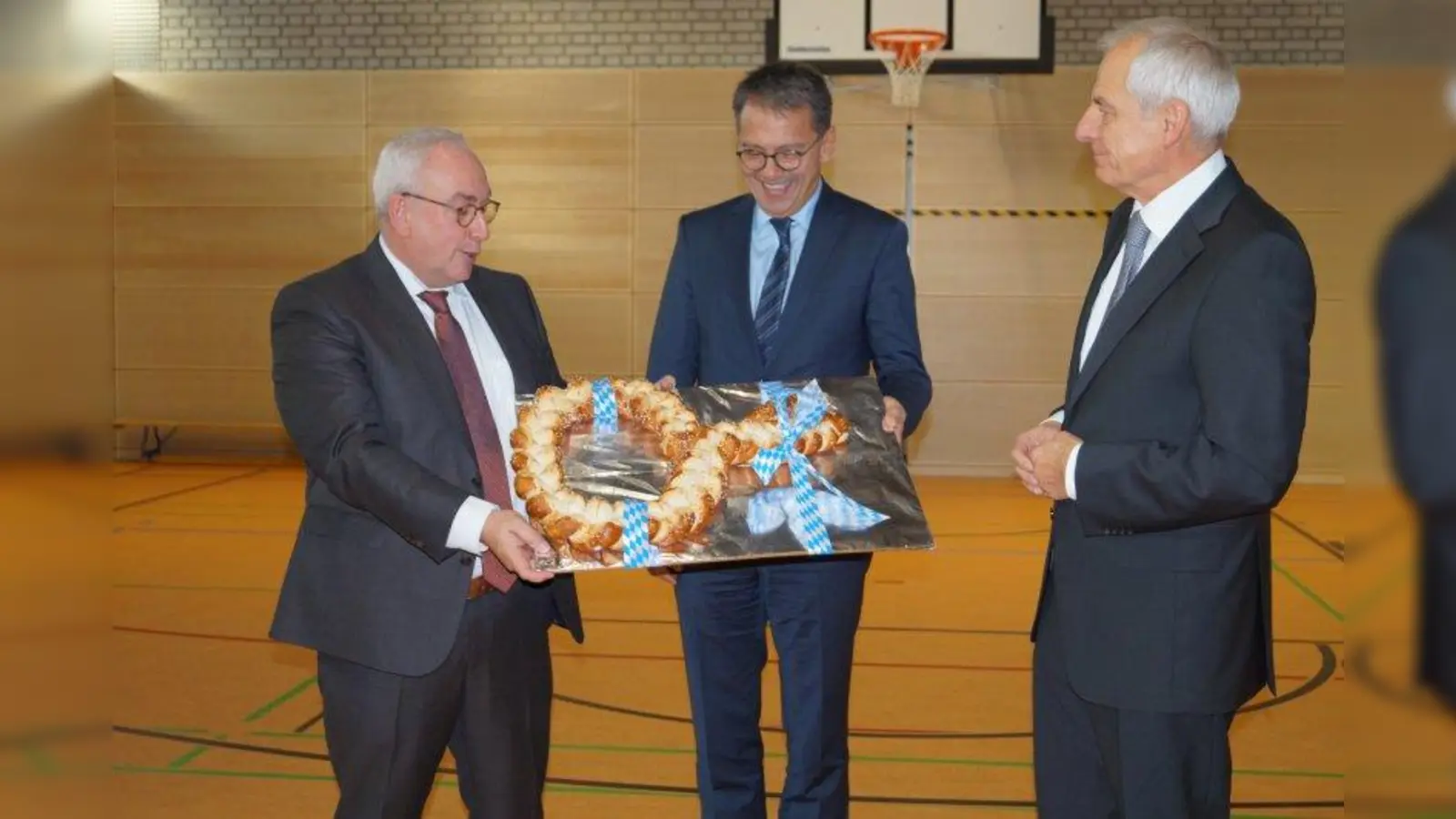Eine Breze als symbolischer Schlüssel bekam Oberstudiendirektor Dr. Robert Christoph (links) von  Landrat Thomas Karmasin und Architekt Dieter Haake (rechts) überreicht. (Foto: pst)