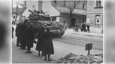 Am 30. April 1945 rücken amerikanischer Panzer in der Plinganserstraße vor (im Hintergrund St. Achaz). Münchner beobachten den Einmarsch am Straßenrand. (Foto: Stadtarchiv München (FS-PK-ERG-09-0261))