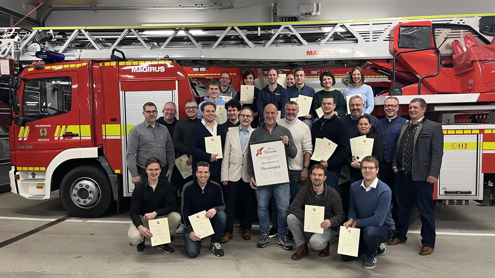 Die Freiwillige Feuerwehr u.a. mit 1. Kommandant Felix Lechner (rechts), 2. Kommandant Philipp Hergert (links stehend), Vorsitzendem Andreas Böll (Mitte, weißes Sakko), Ehrenmitglied Konrad Grabmaier (Mitte, große Urkunde) und stv. Vorsitzendem Ernst Marschke (Mitte, heller Pulli). (Foto: FFW)